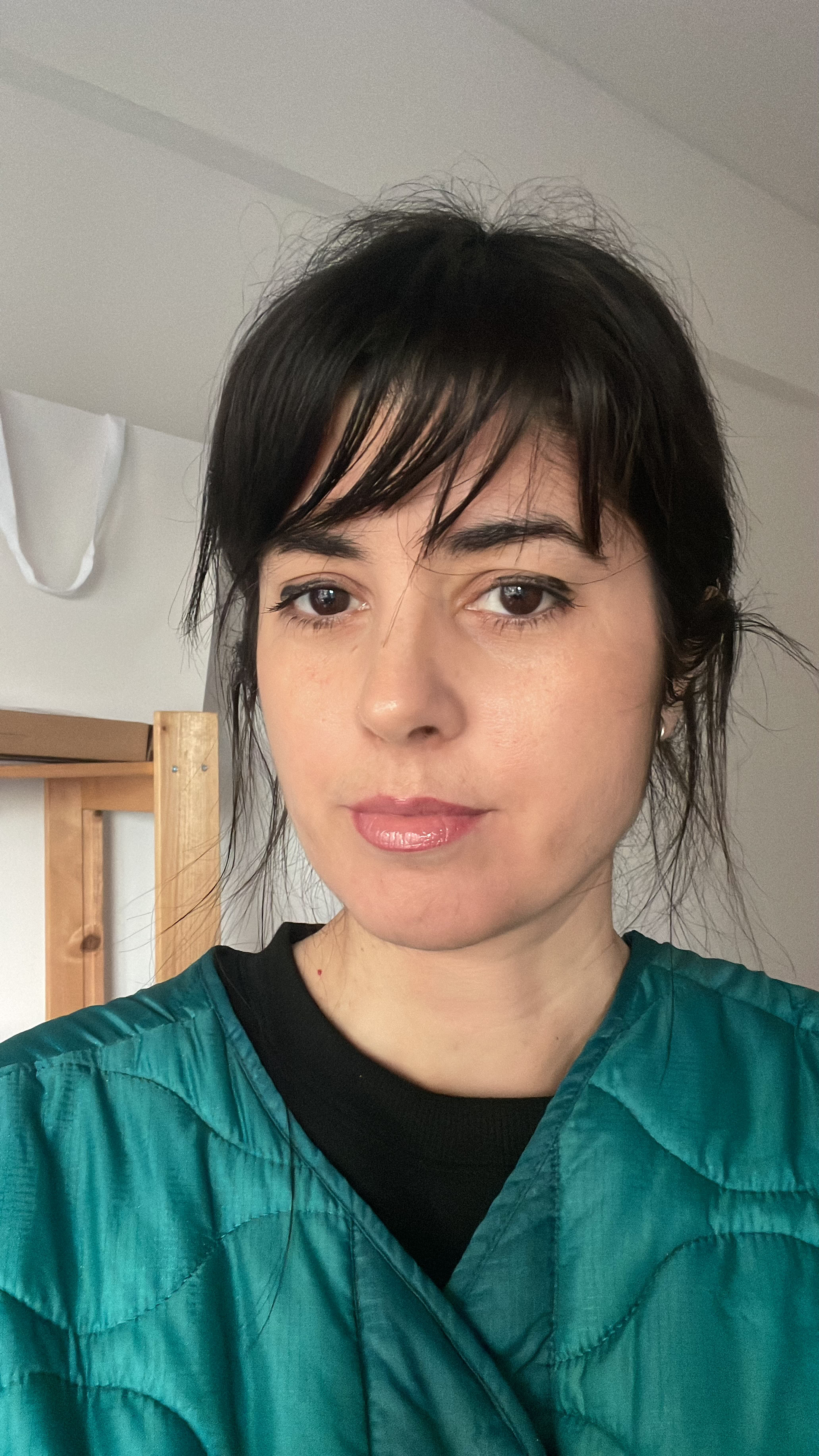 Portrait of a woman with brown hair on a flat gray background.